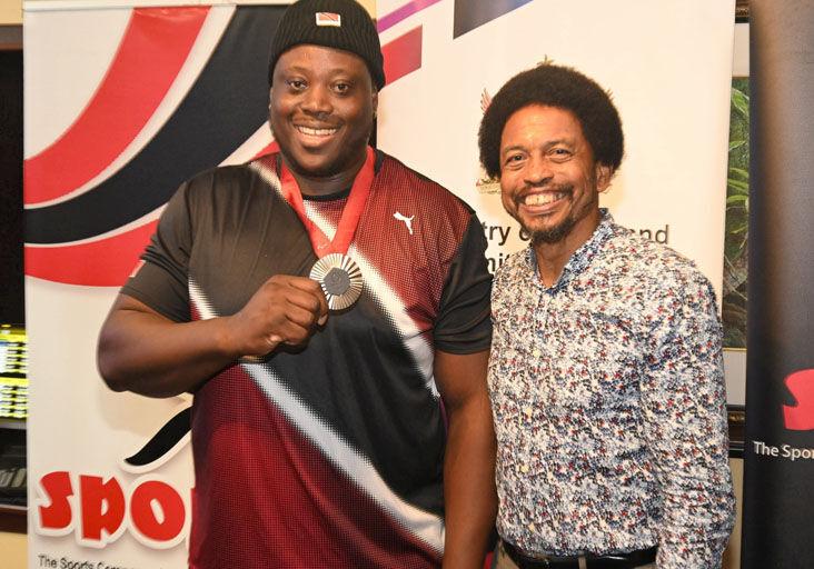 RICH REWARD: T&T para-athlete Akeem Stewart displays his silver medal in the company of former president of the Trinidad and Tobago Olympic Committee Brian Lewis, during a reception in his honour at Piarco International Airport, last month. Stewart was the runner-up in the men’s discus throw F64 event at the 2024 Paralympic Games, in Paris, France, last month. —Photo: CURTIS CHASE (Image obtained at trinidadexpress.com)